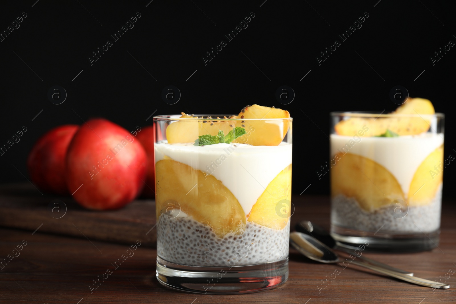 Photo of Tasty peach dessert with yogurt and chia seeds served on wooden table