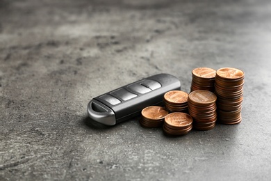 Car key and coins on grey background. Space for text