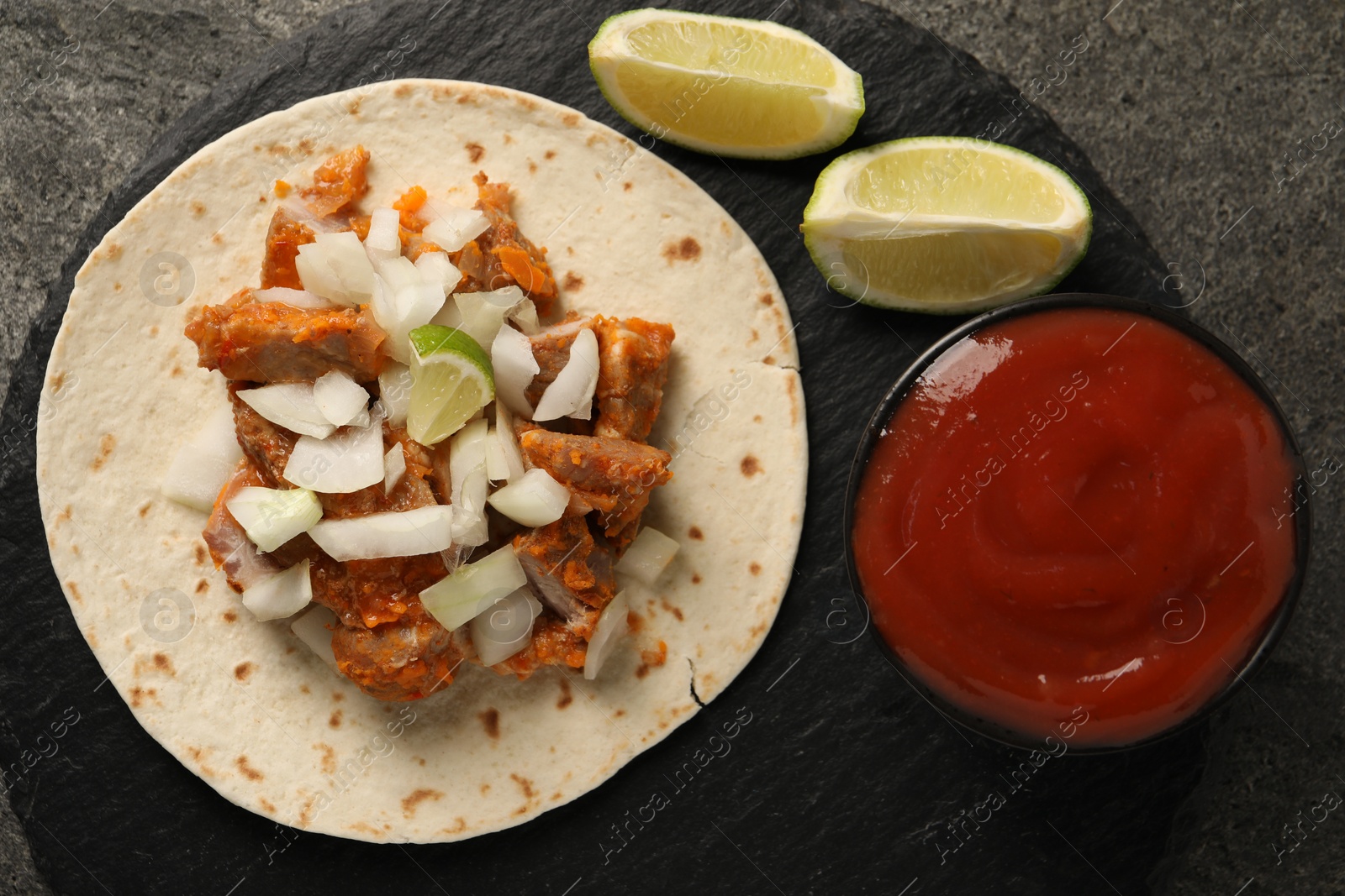 Photo of Delicious taco with vegetables, meat and ketchup on grey textured table, top view