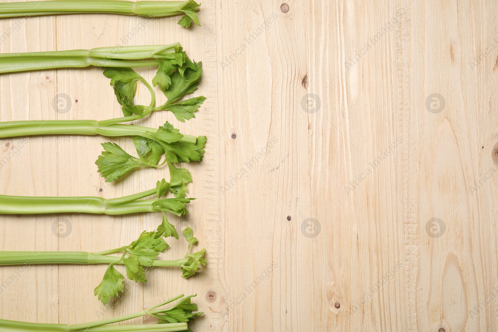 Photo of Fresh green celery on wooden table, flat lay. Space for text