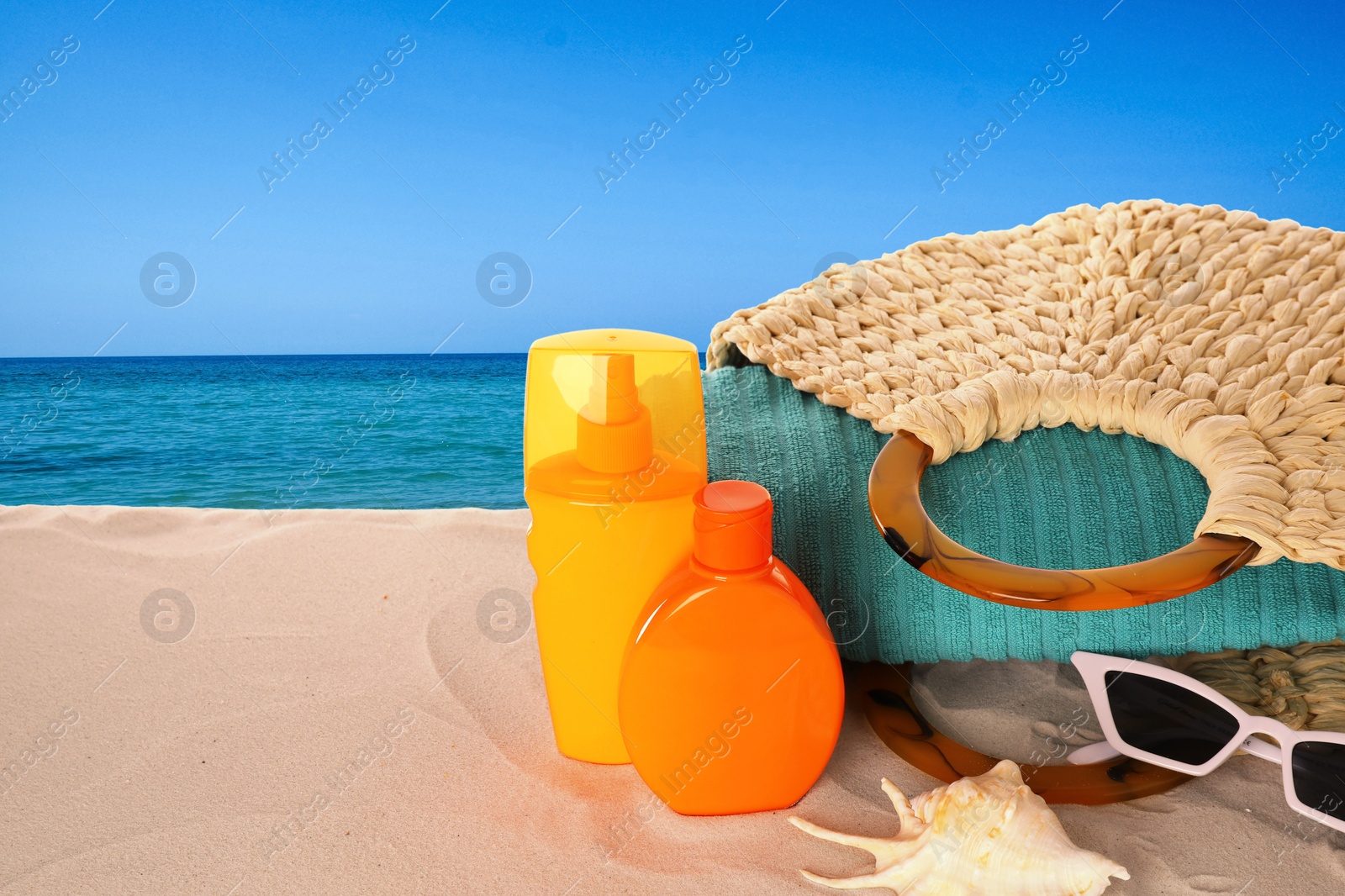 Image of Set of sun protection products and stylish accessories on sandy beach