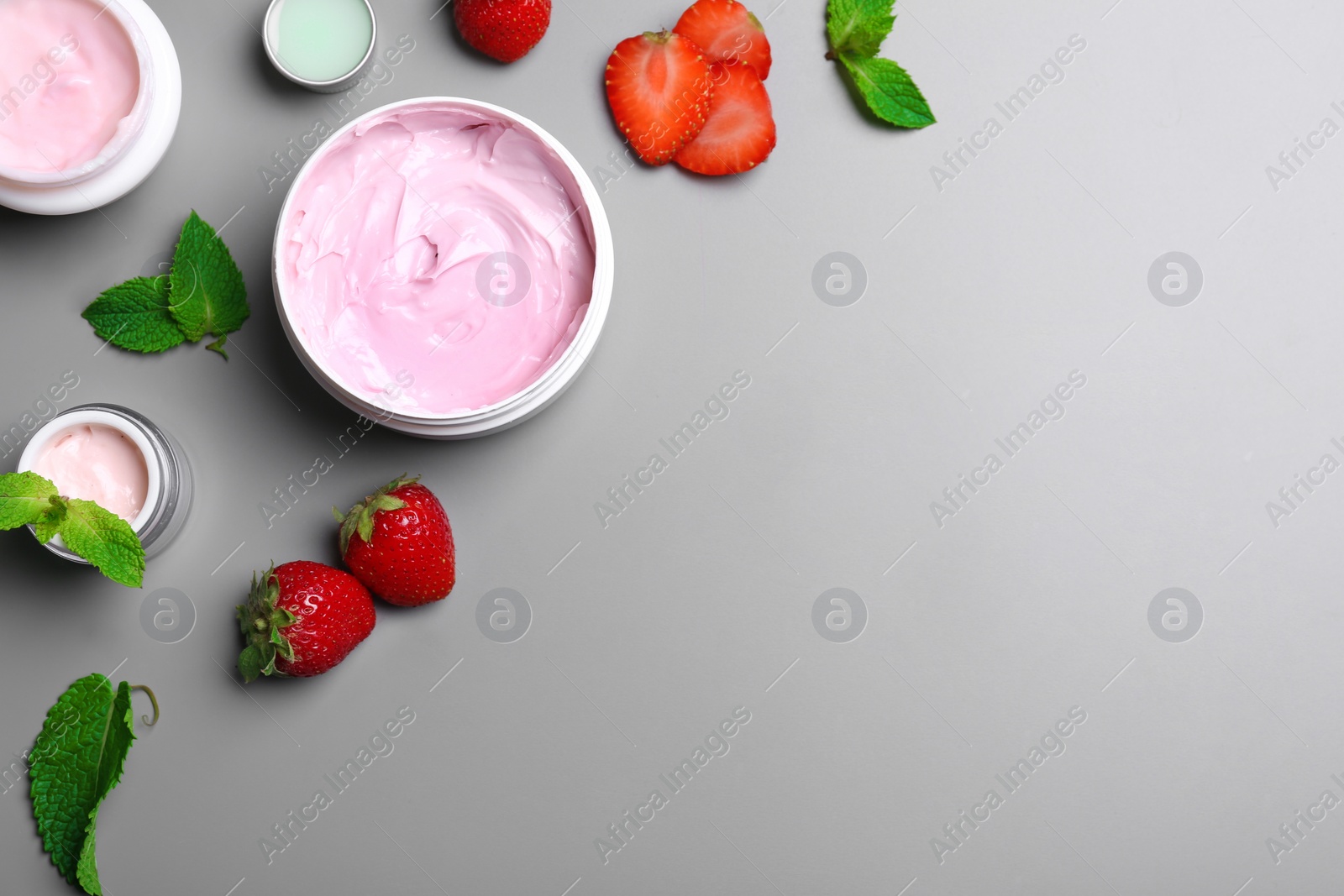 Photo of Flat lay composition with jars of body cream on grey background. Space for text