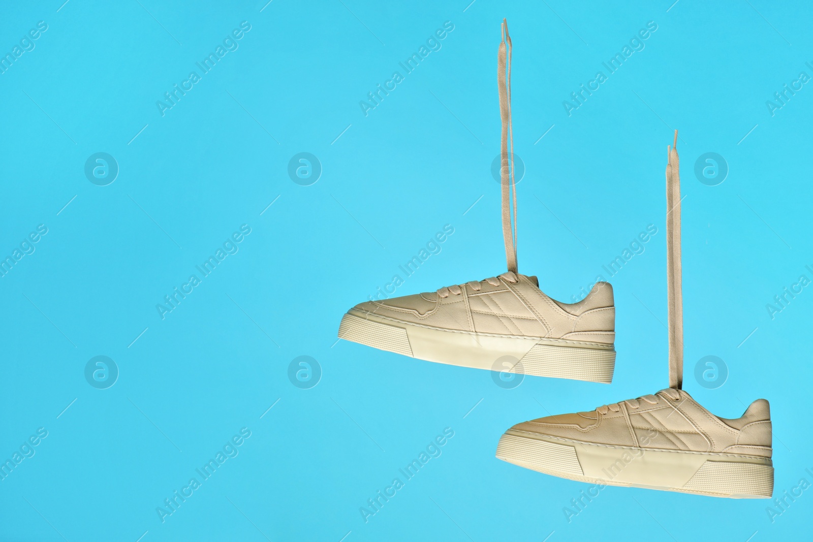 Photo of Pair of stylish white sneakers on blue background, space for text