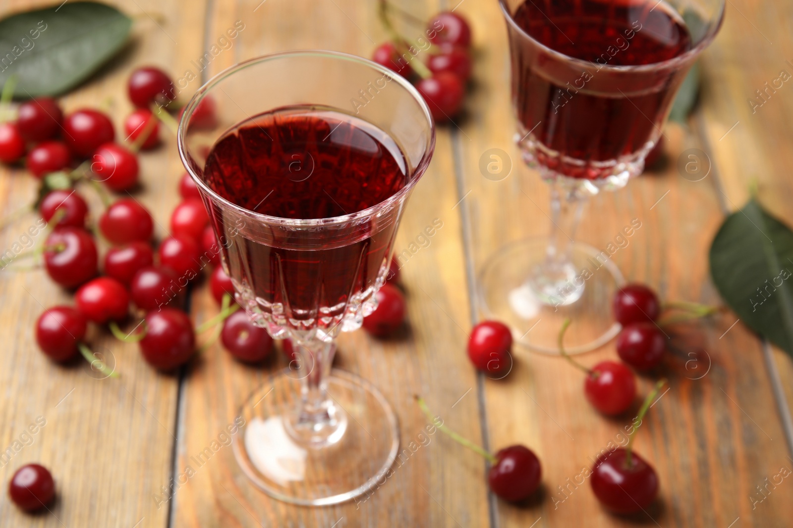 Photo of Delicious cherry wine with ripe juicy berries on wooden table