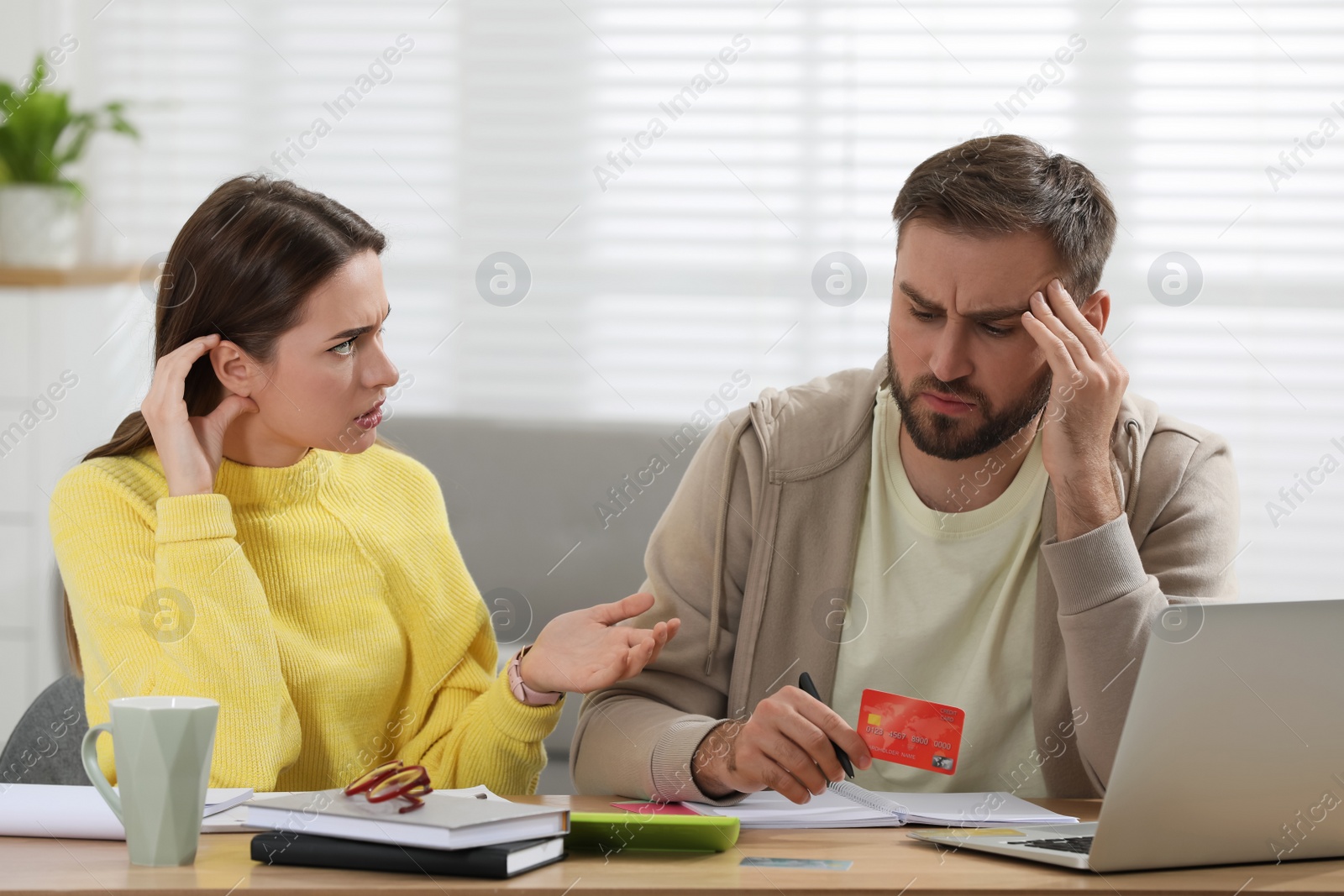 Photo of Young couple discussing family budget at table in living room