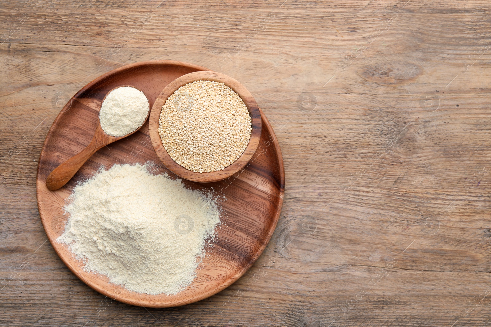 Photo of Pile of quinoa flour and seeds in bowl on wooden table, top view. Space for text