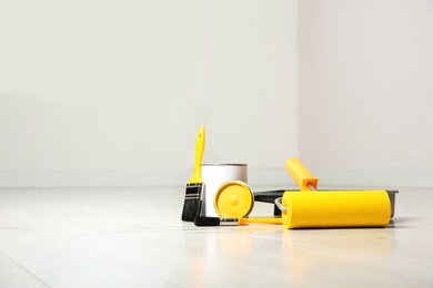 Photo of Can of paint and decorator tools on wooden floor indoors. Space for text