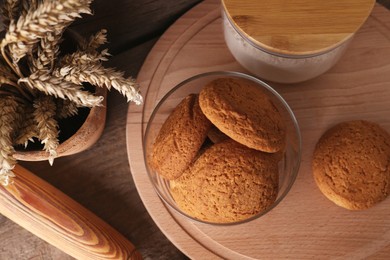 Photo of Cookies and wheat spikes on wooden table, flat lay