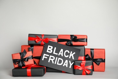 Many gift boxes and sheet of paper with words Black Friday on light grey background. Space for text