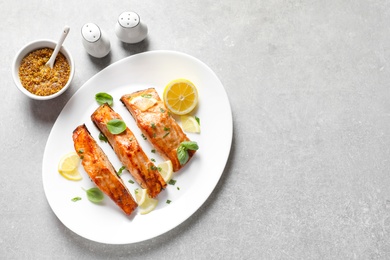 Plate with tasty cooked salmon served for dinner on table, top view