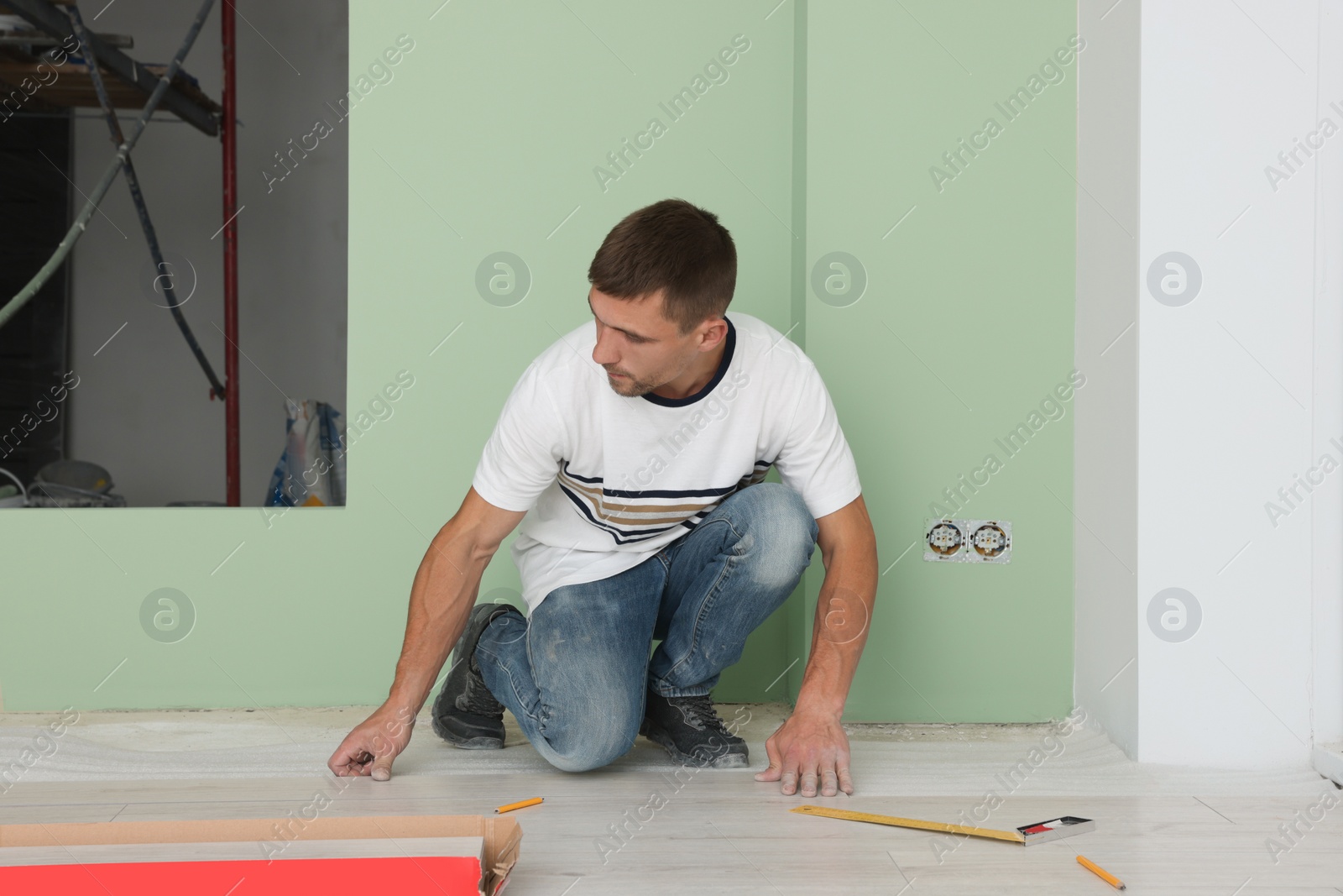 Photo of Man installing new laminate flooring in room