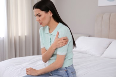 Photo of Woman suffering from shoulder pain on bed at home