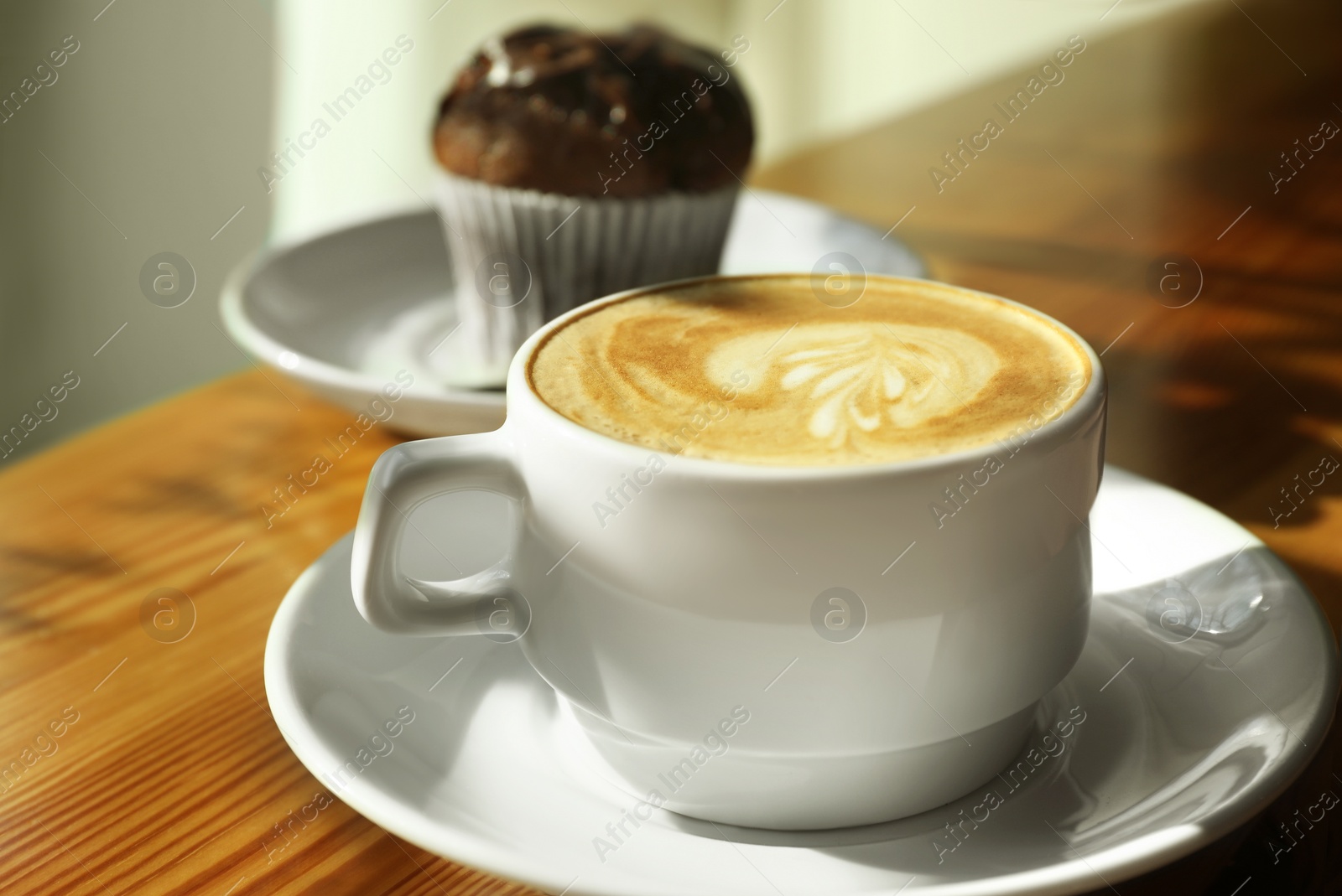 Photo of Cup of fresh aromatic coffee and cupcake at table in cafe