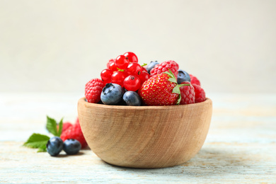 Photo of Mix of different fresh berries in bowl on wooden table