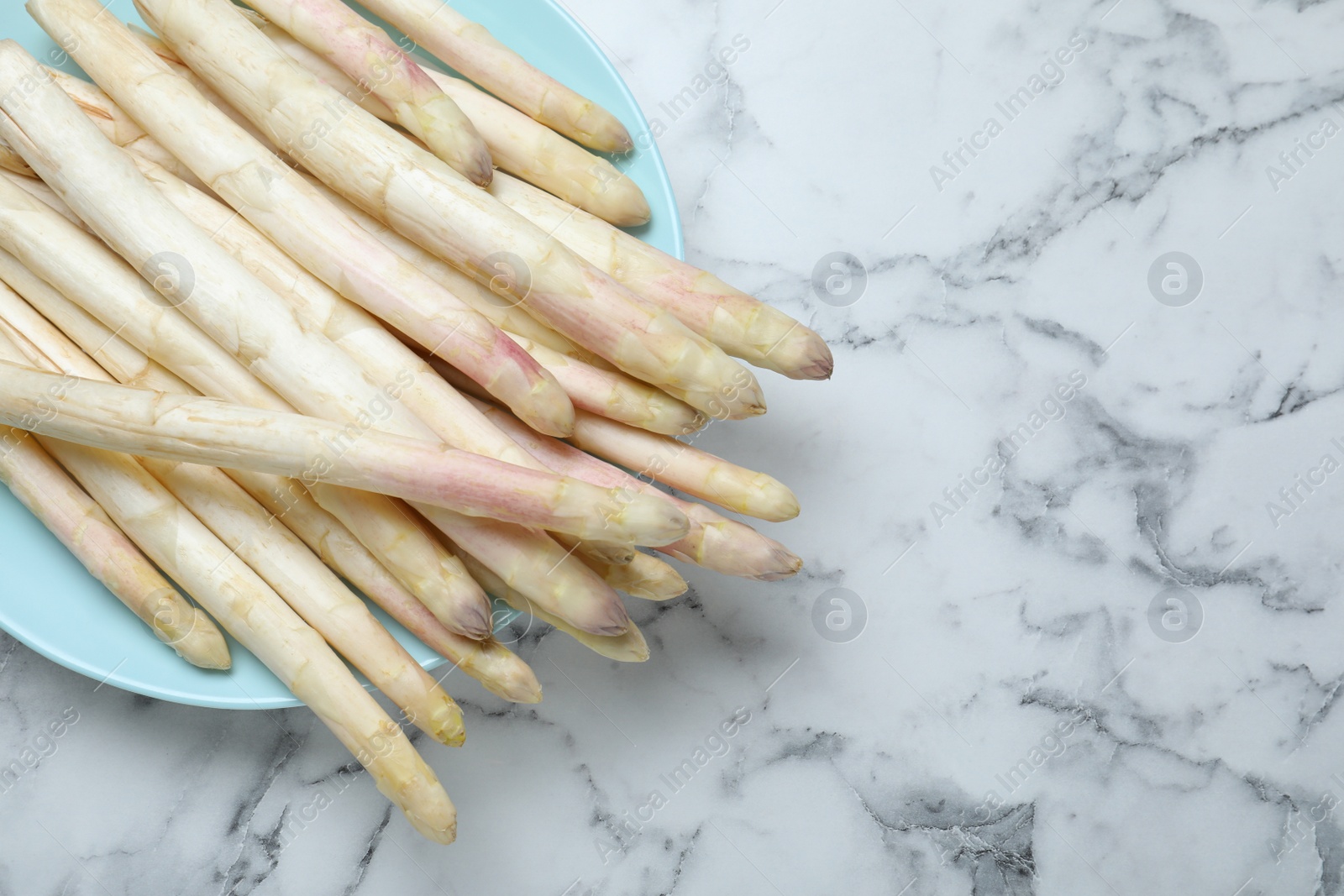 Photo of Fresh white asparagus on marble table, top view. Space for text