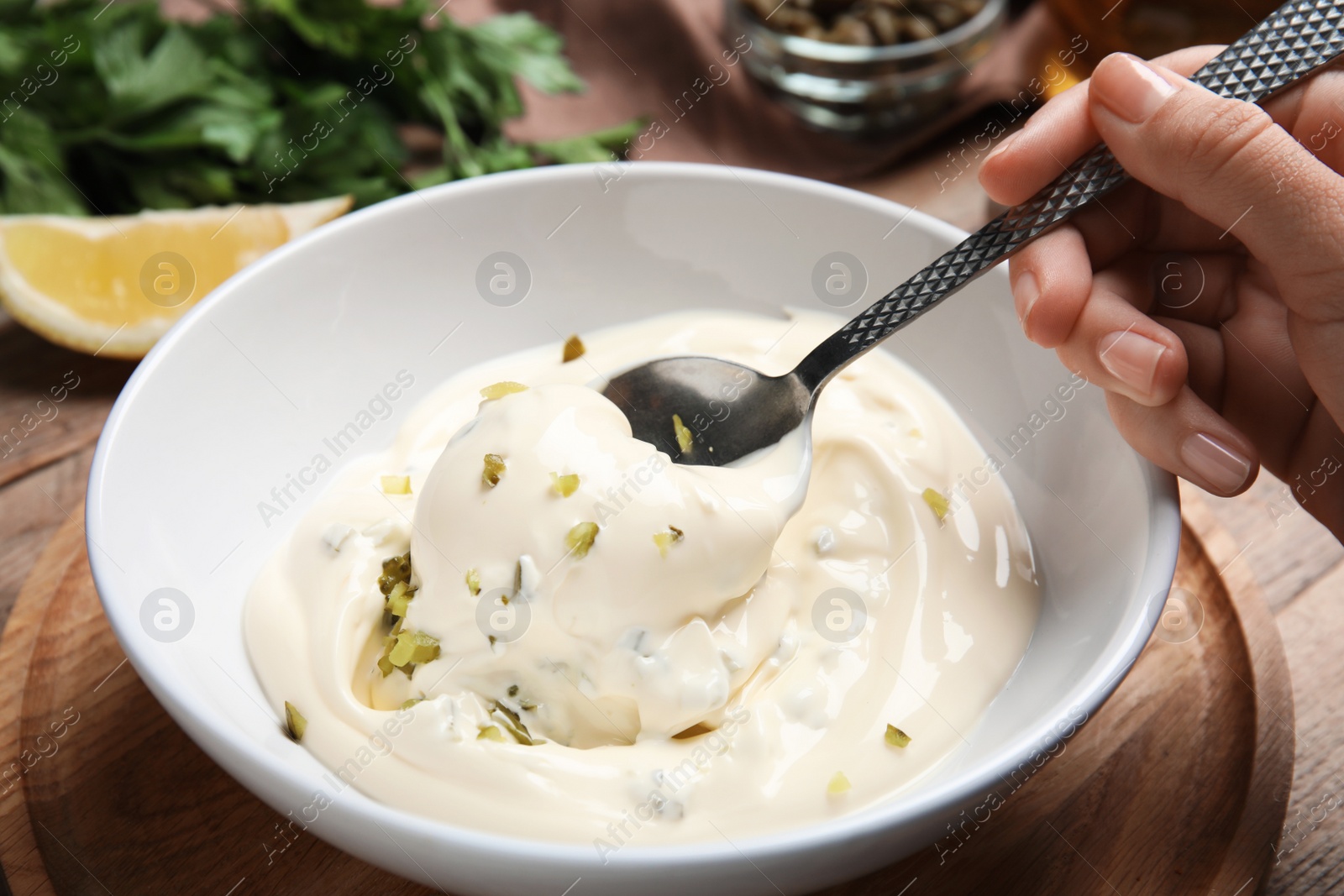 Photo of Woman making delicious tartar sauce at wooden table, closeup