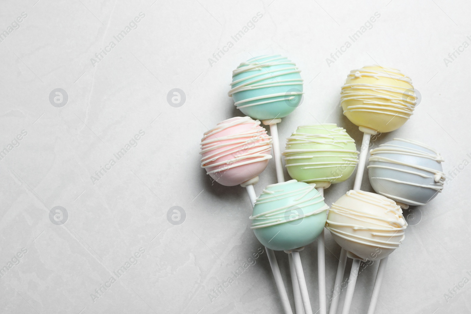 Photo of Sweet colorful cake pops on light grey background, flat lay