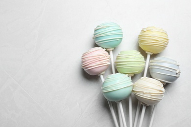 Sweet colorful cake pops on light grey background, flat lay