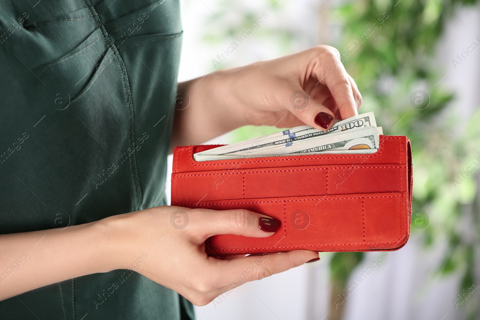 Photo of Woman putting money into wallet on blurred background, closeup