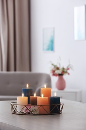 Tray with burning candles and flowers on table in living room. Space for text