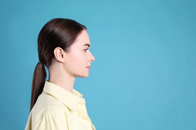 Photo of Profile portrait of young woman on light blue background. Space for text