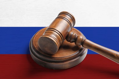 Image of Judge's gavel on wooden background in color of Russian flag. Concept of sanctions against Russia