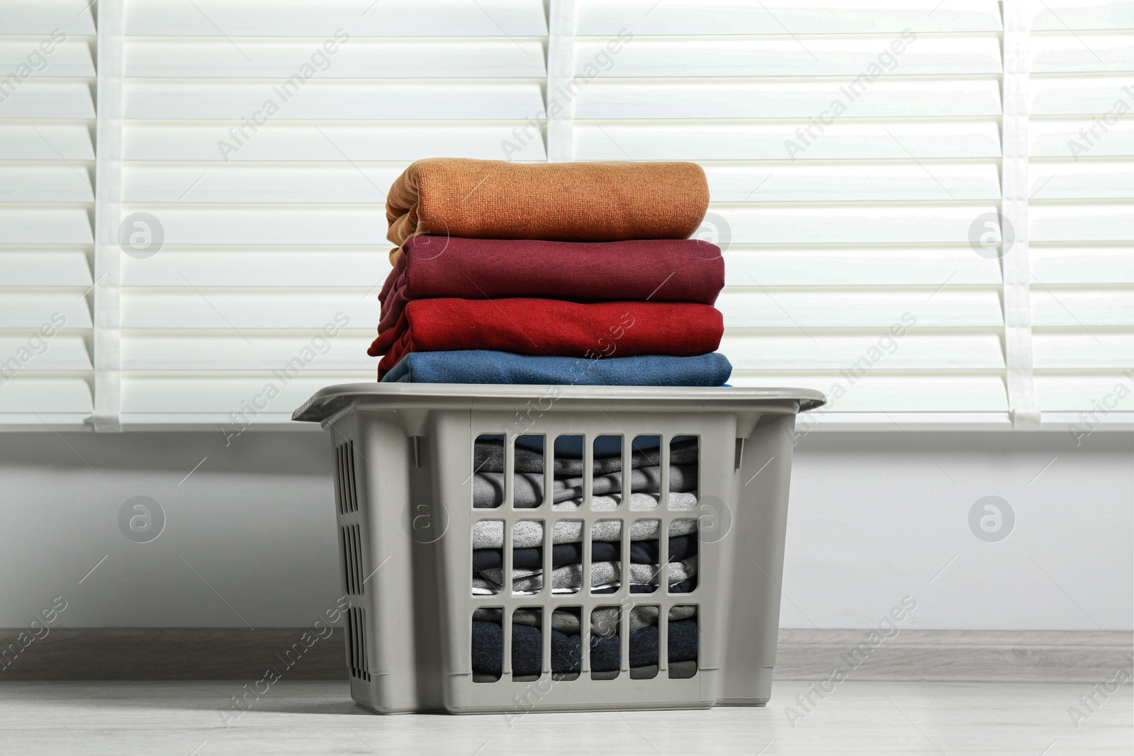 Photo of Plastic laundry basket with clean clothes indoors