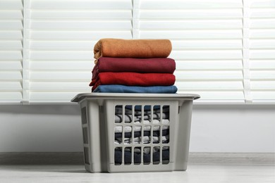 Photo of Plastic laundry basket with clean clothes indoors