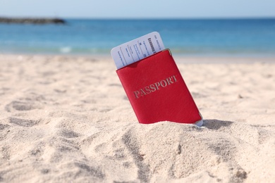 Passport with airline ticket in sand on beach