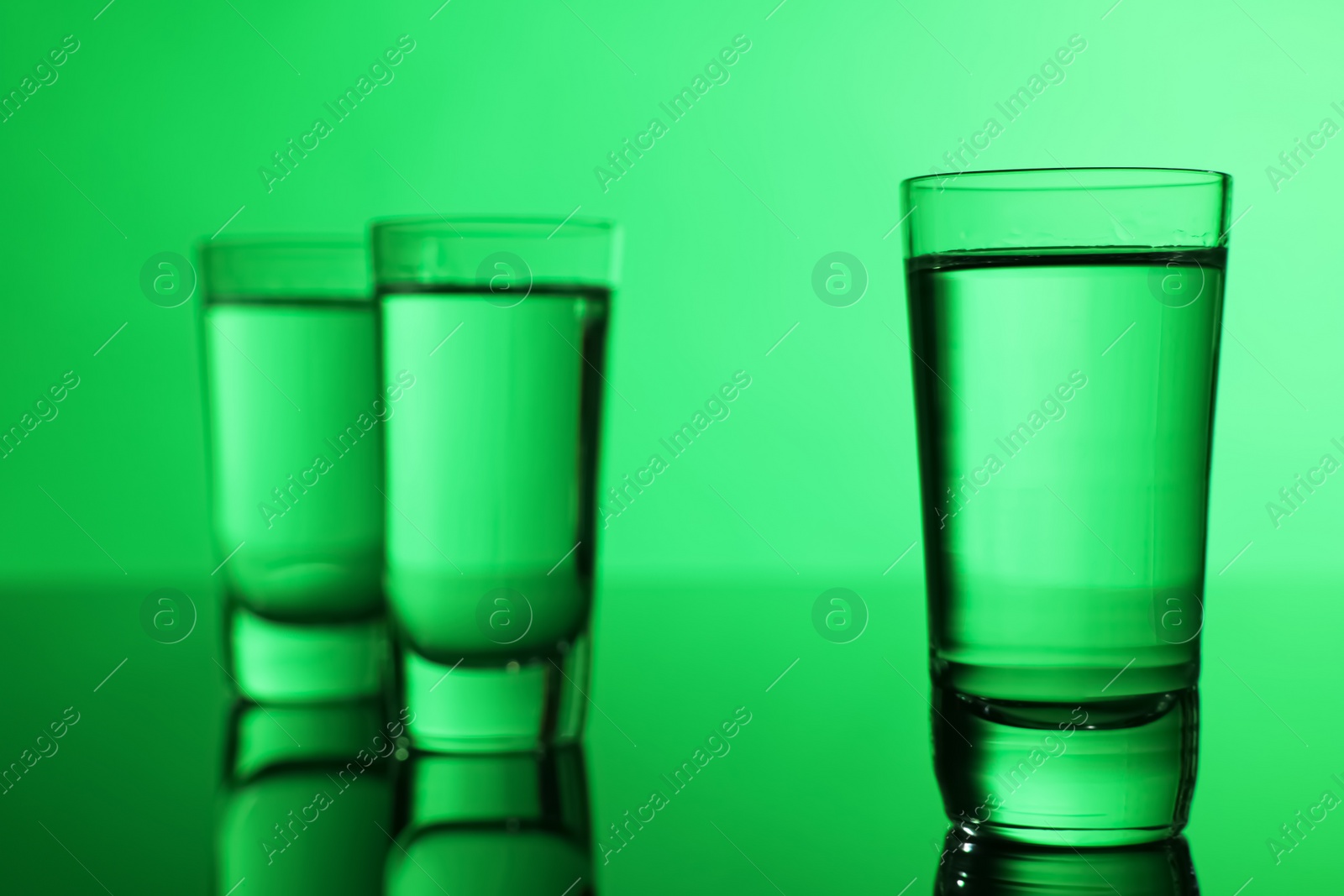 Photo of Vodka on table against green background, space for text