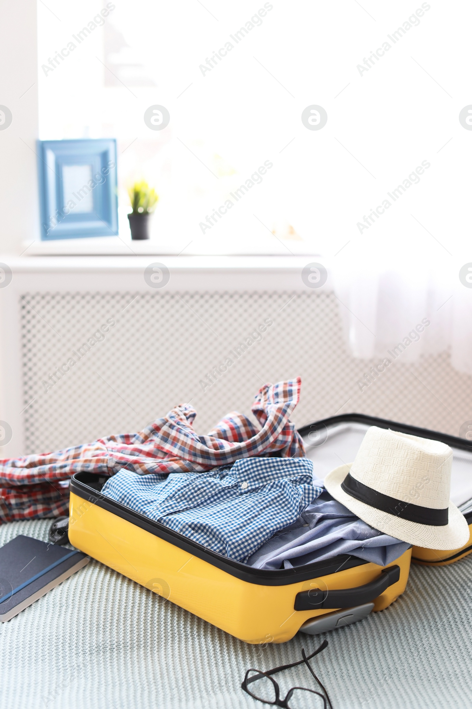 Photo of Open suitcase with packed clothes on bed