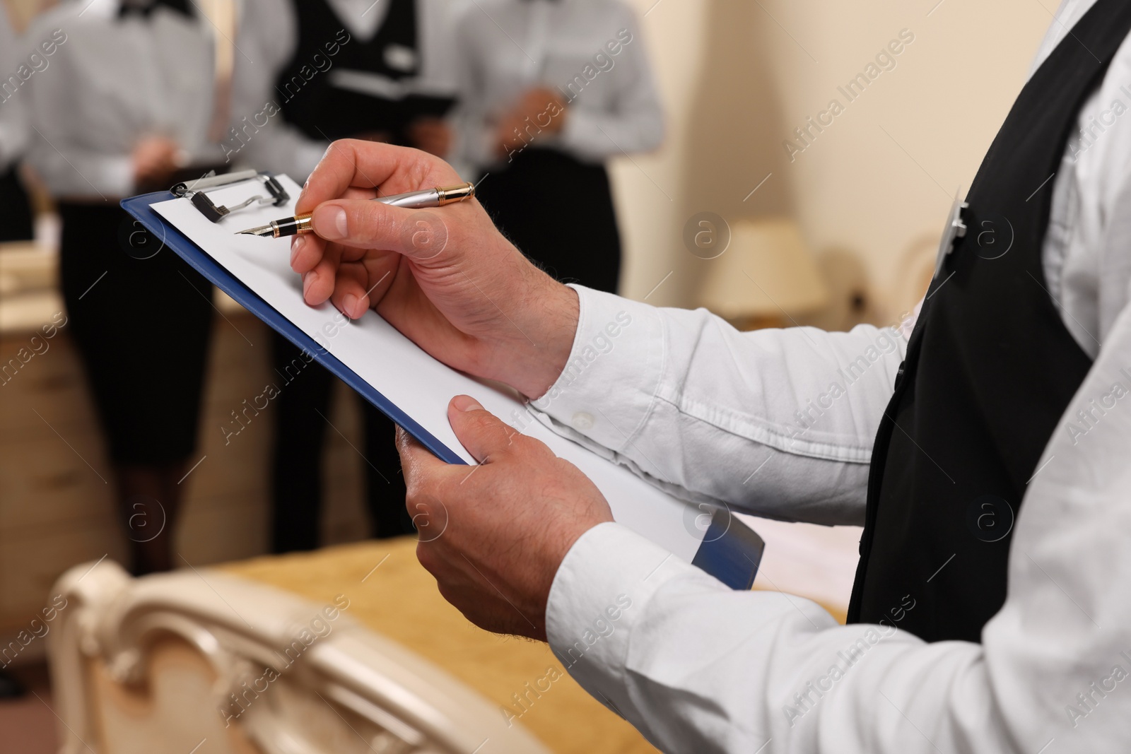 Photo of Man in suit with clipboard indoors, closeup. Professional butler courses
