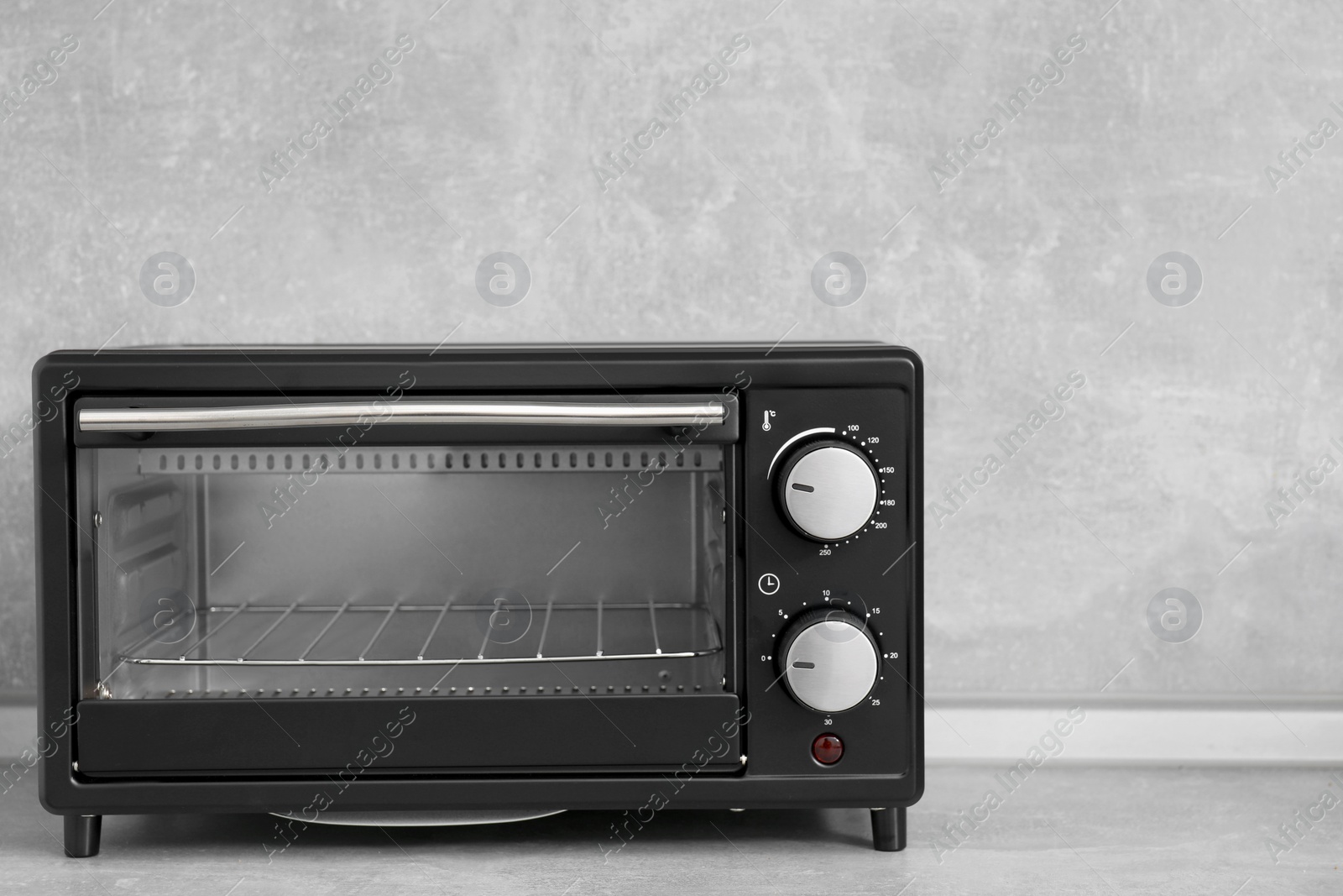 Photo of One electric oven on light grey table. Cooking appliance