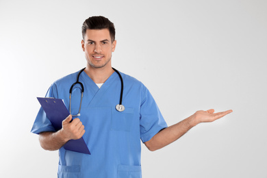 Photo of Doctor with stethoscope and clipboard on light grey background