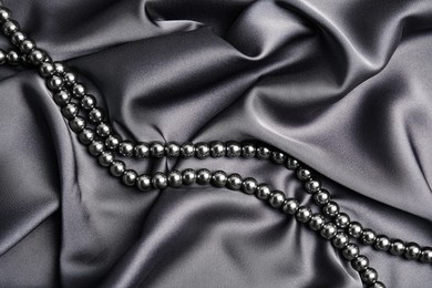 Photo of Beautiful pearls on grey silk, top view