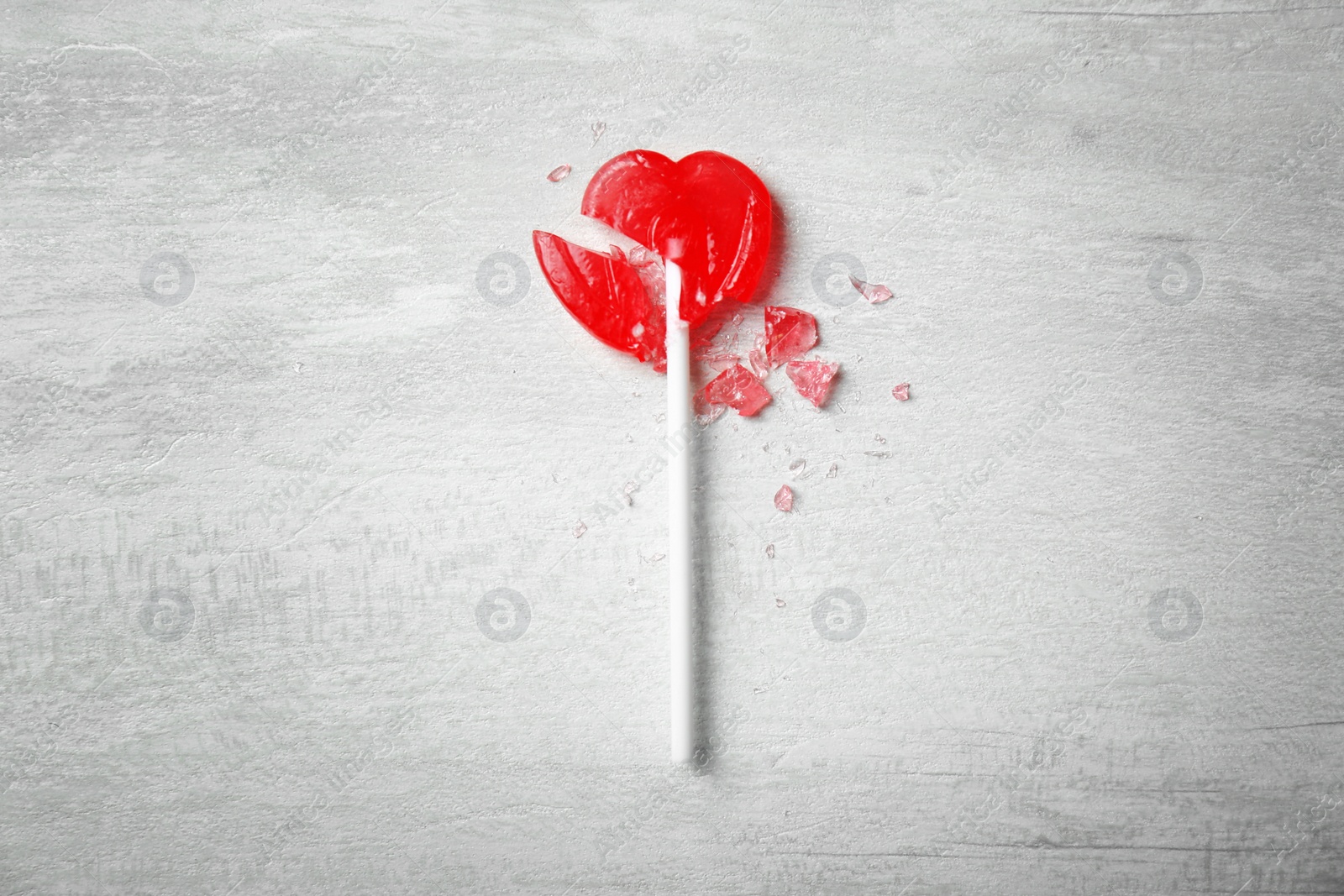 Photo of Broken heart shaped lollipop on gray background, top view. Relationship problems