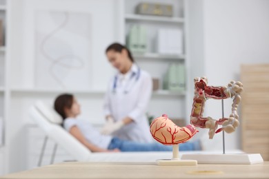 Gastroenterologist examining girl in clinic, focus on models of stomach and intestine on table