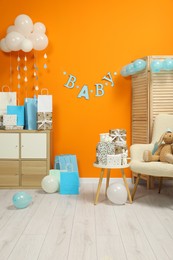 Photo of Baby shower party. Festive decor, booties, toys and gift boxes in stylish room