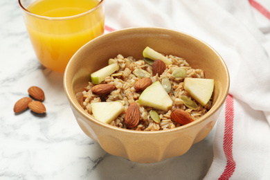 Photo of Tasty oatmeal with apples and almonds on marble table, closeup. Healthy breakfast