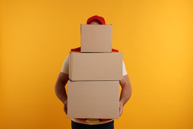 Courier with stack of parcels on orange background