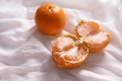 Photo of Fresh ripe tangerines on white cloth, closeup. Space for text