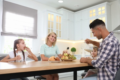 Photo of Happy family eating together at table in modern kitchen