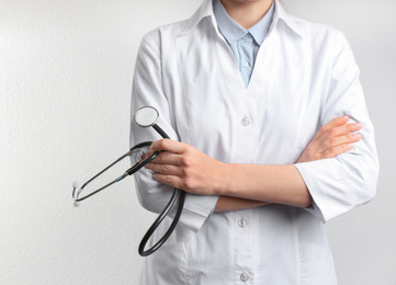 Doctor with stethoscope on white background, closeup. Medical service