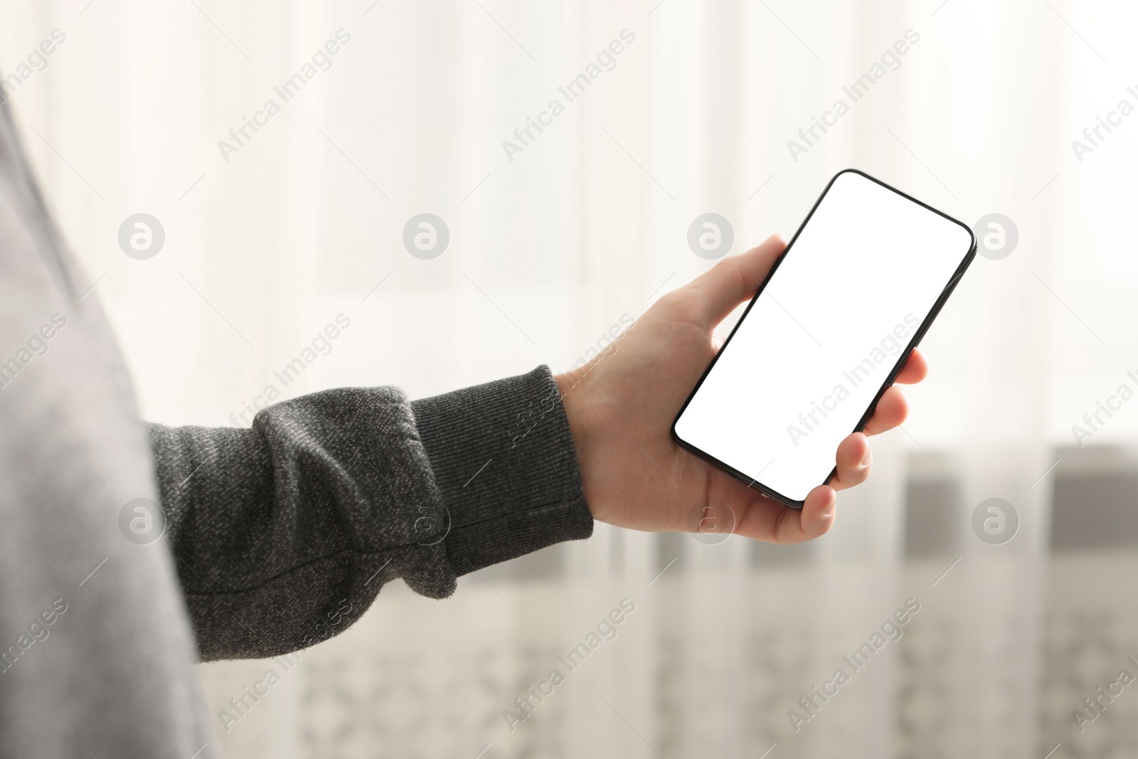 Photo of Man using smartphone with blank screen indoors, closeup. Mockup for design