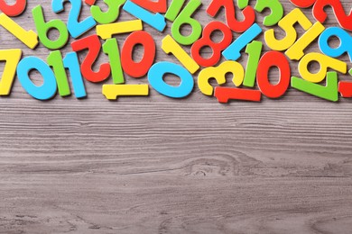 Photo of Colorful numbers on wooden school desk, flat lay. Space for text