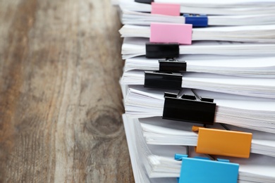 Photo of Documents with colorful binder clips on wooden table, closeup
