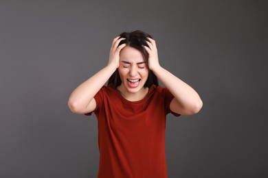 Portrait of emotional young woman on dark grey background. Personality concept