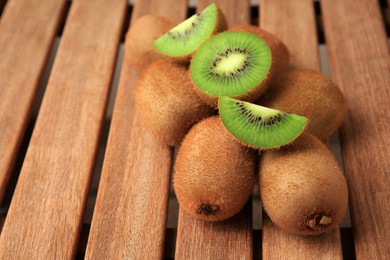 Whole and cut kiwis on wooden table, closeup. Space for text