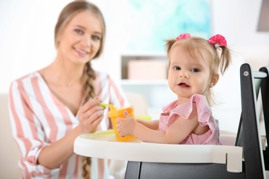 Photo of Caring mother feeding her cute little baby with healthy food at home