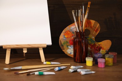 Easel with canvas and art supplies on wooden table